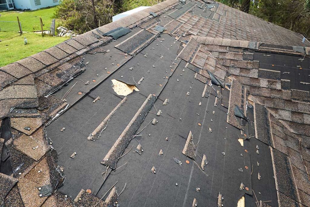 Residential home with asphalt shingles and a metal roof section covered in light snow
